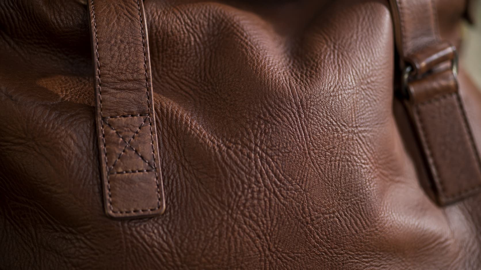 Close-up of real leather grain texture showing natural wrinkles and stitching