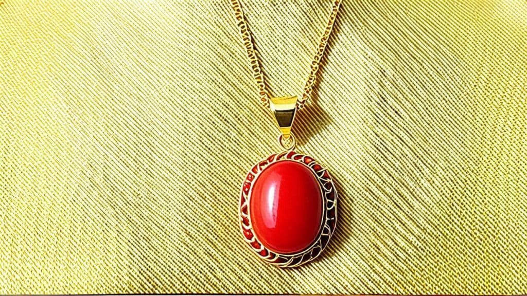 Gold necklace featuring an oval red coral gemstone pendant, showcasing the vibrant hue and natural elegance of organic coral jewelry.