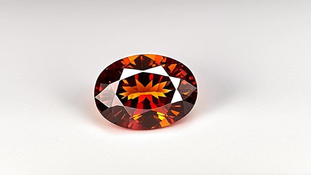 Oval-cut spessartine garnet with a reddish-orange hue, representing the deeper end of the spessartine-almandine color range.