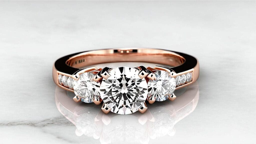 Rose gold three-stone engagement ring with round brilliant diamonds and pavé side stones on a polished band.