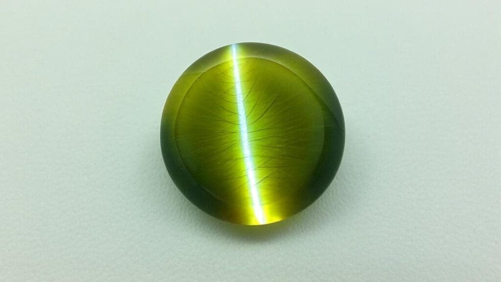 Round green cat’s eye gemstone with fibrous internal inclusions creating a bright eye effect
