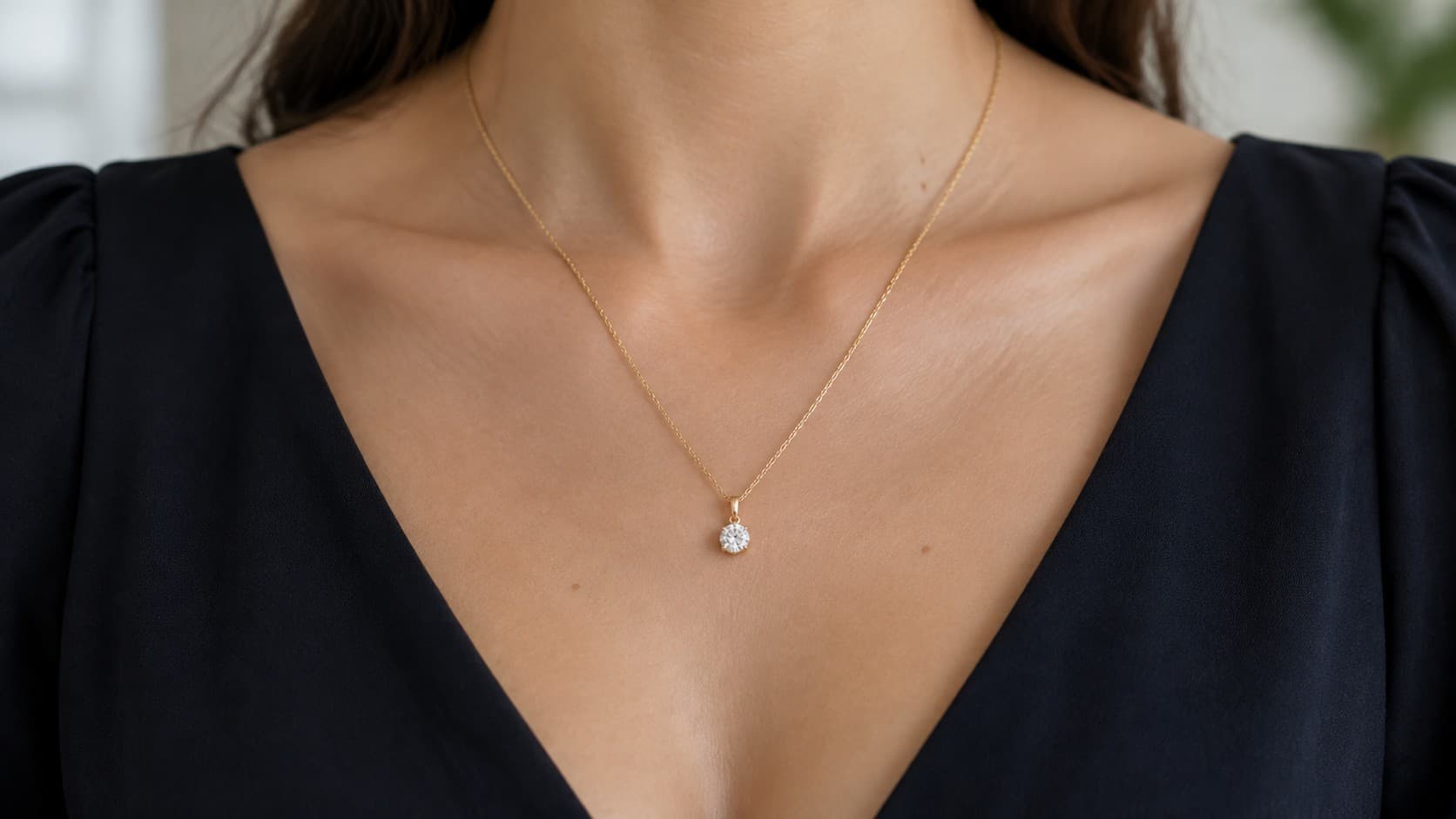 Woman wearing a thin gold pendant necklace with a black V-neck top, styled for a semi-formal event