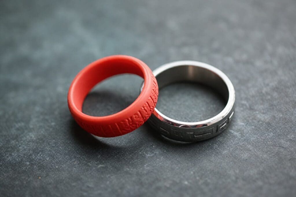 Red silicone ring next to traditional metal wedding band, comparing pregnancy-safe jewelry alternatives