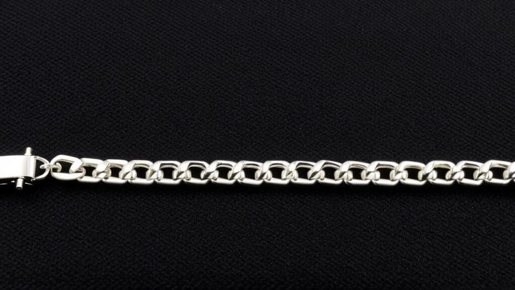 Silver Cuban link bracelet with polished finish displayed on black fabric