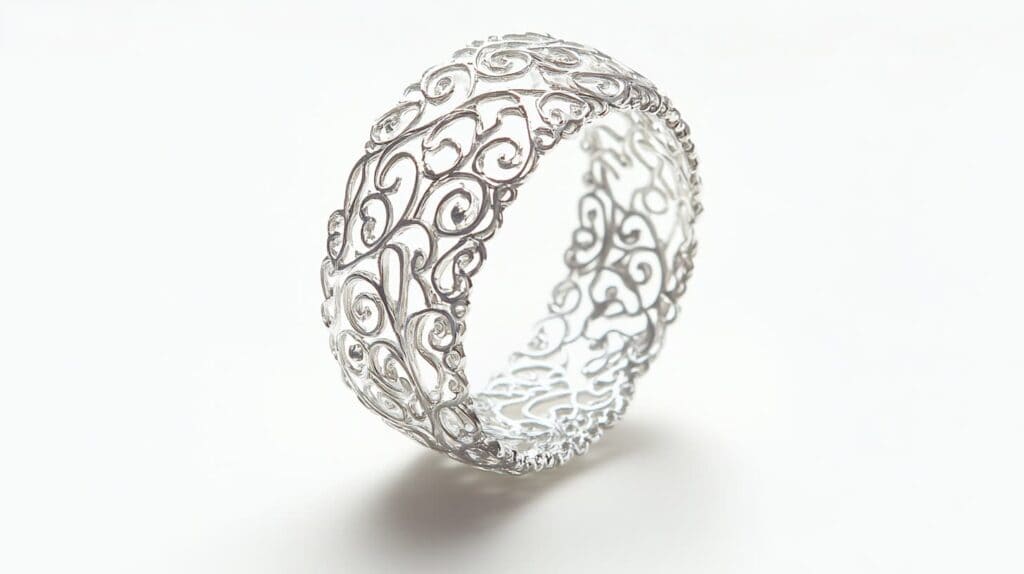 A silver filigree ring featuring intricate swirling patterns and openwork design, showcasing detailed craftsmanship.