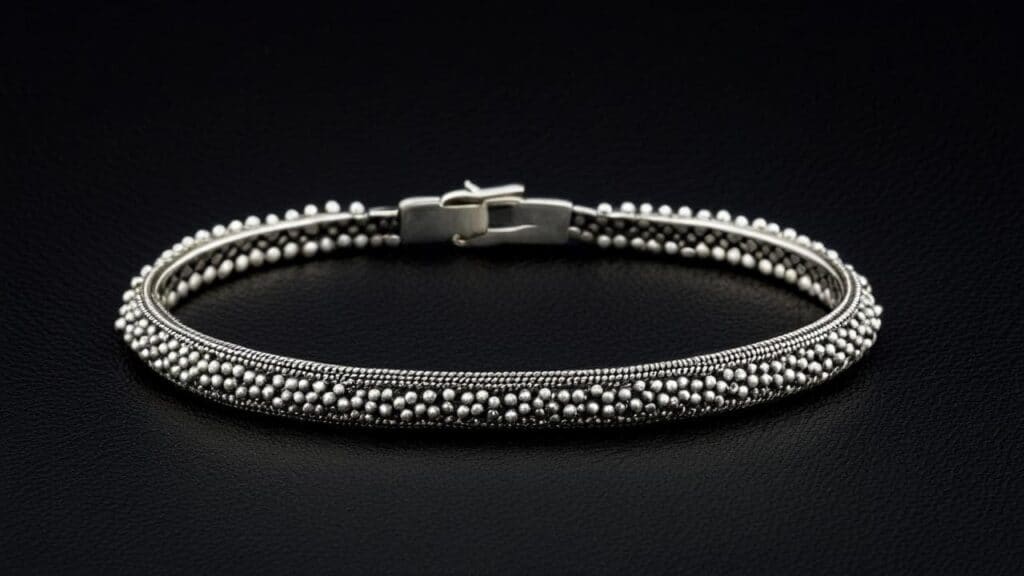 A finely crafted silver bracelet with intricate granulation, featuring rows of tiny silver spheres for a detailed textured look.