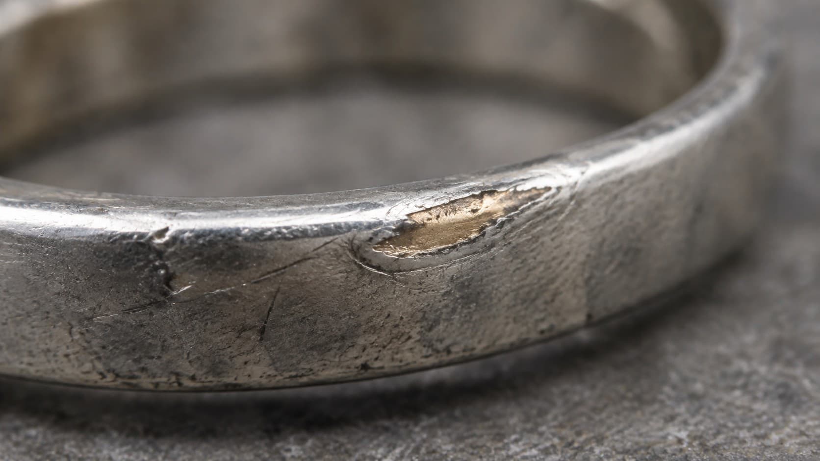Close-up of a worn silver ring edge showing the base metal underneath the plating