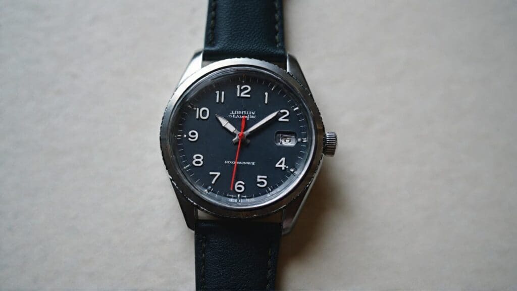 Clean black dial watch with leather strap showing basic watchmaking fundamentals and simple timepiece design
