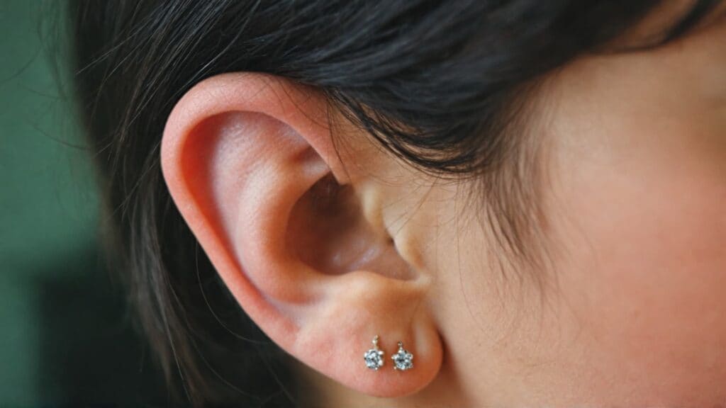 Simple diamond or crystal stud earrings in earlobe piercings showing child-safe jewelry options for new piercings