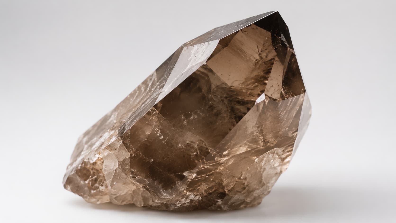 Raw smoky quartz crystal point with natural brown color on a white background