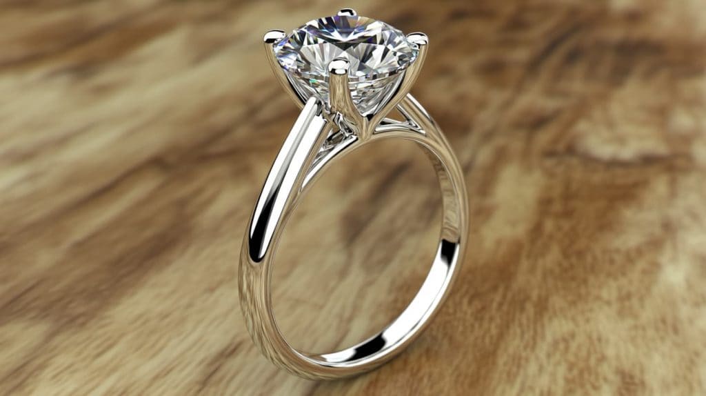 A classic solitaire diamond engagement ring on a wooden table, featuring a sleek and elegant design.
