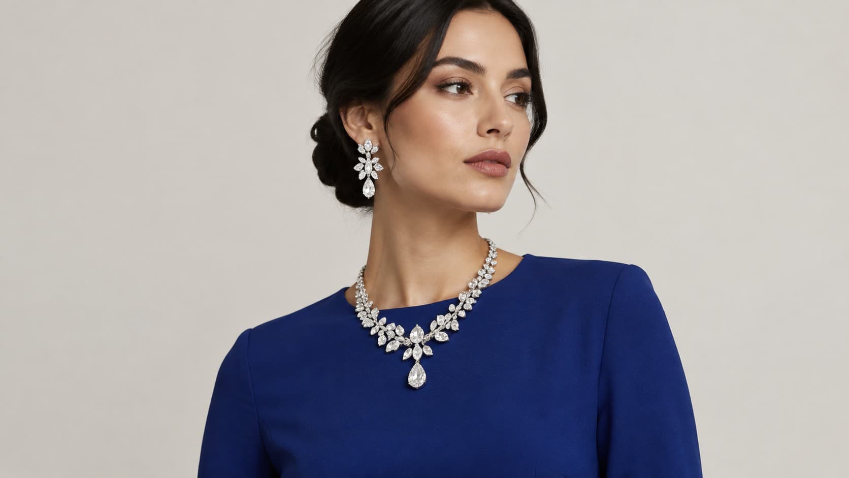 Woman wearing a bold crystal statement necklace and matching drop earrings with a navy dress