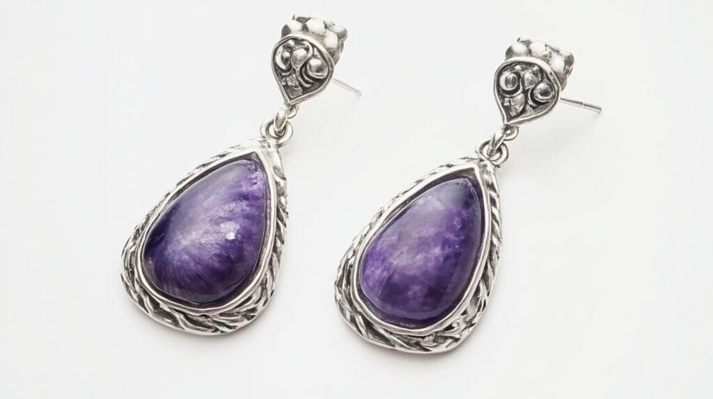 Pair of Sugilite drop earrings with pear-shaped purple cabochon stones in intricately designed silver settings.