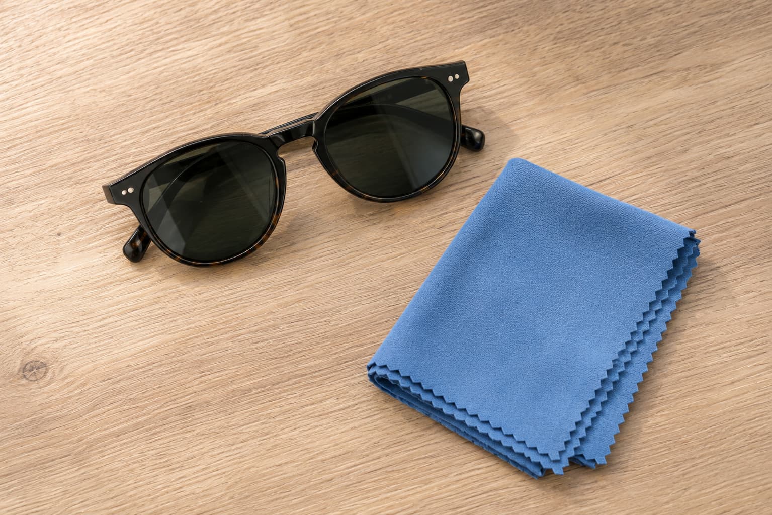 Sunglasses next to a folded blue microfiber cleaning cloth