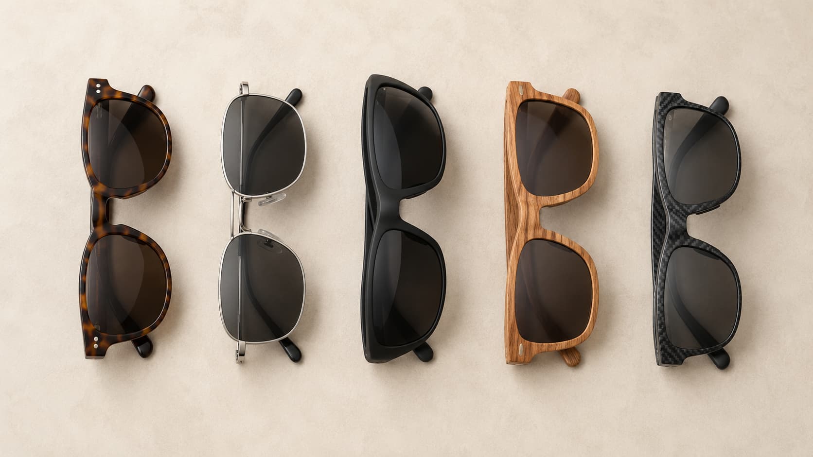 Five folded sunglasses frames lined up side by side, showing acetate, metal, TR-90, wood, and carbon fiber materials