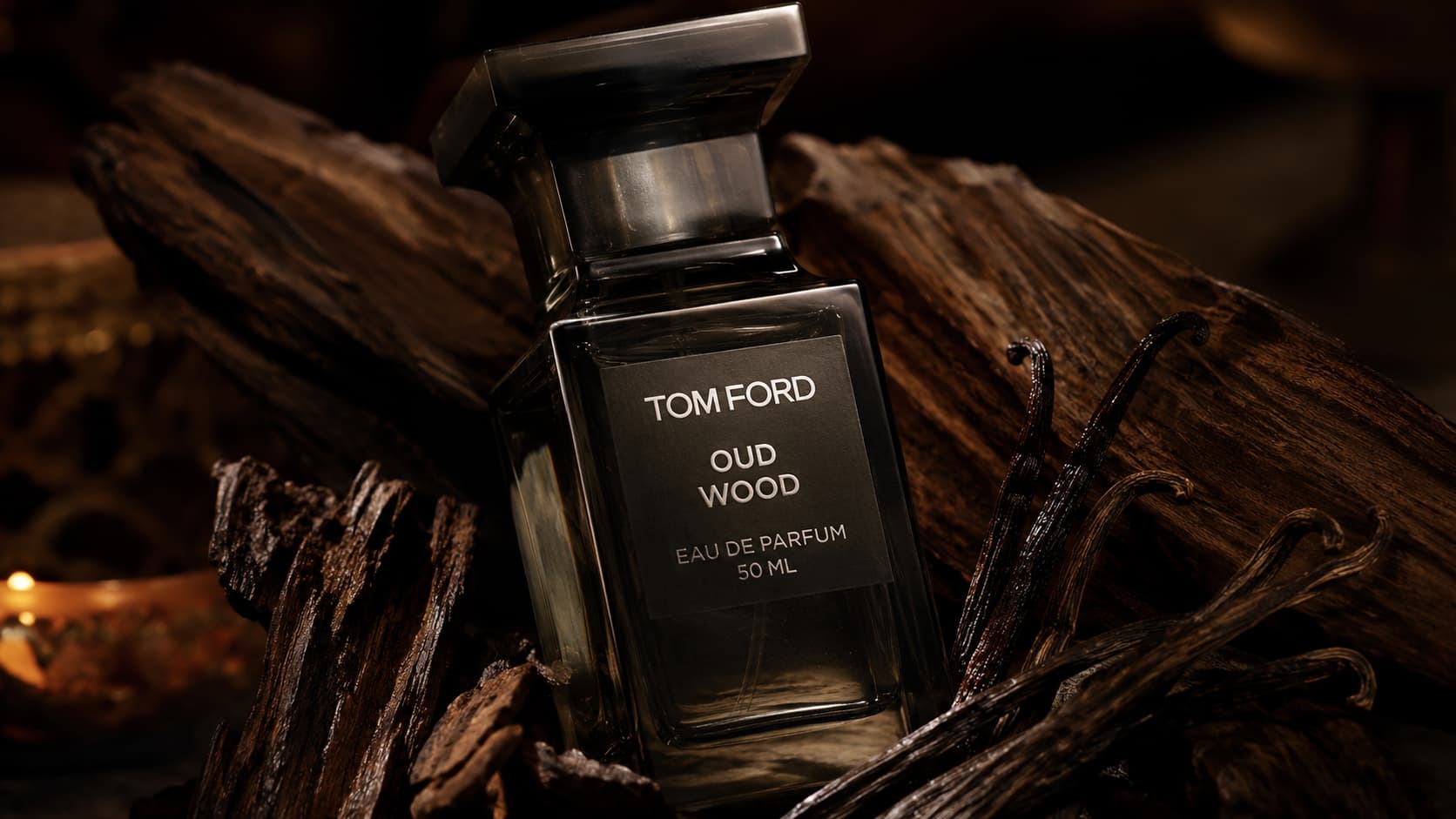 Tom Ford Oud Wood bottle among dark wood and vanilla pods, representing warm base notes