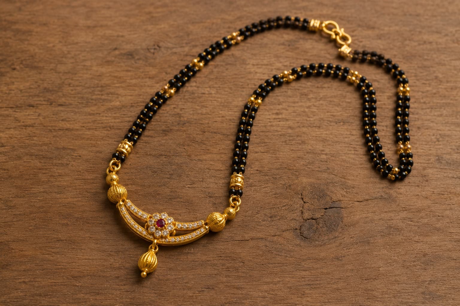 Traditional gold mangalsutra necklace with black beads and a ruby-centered floral pendant