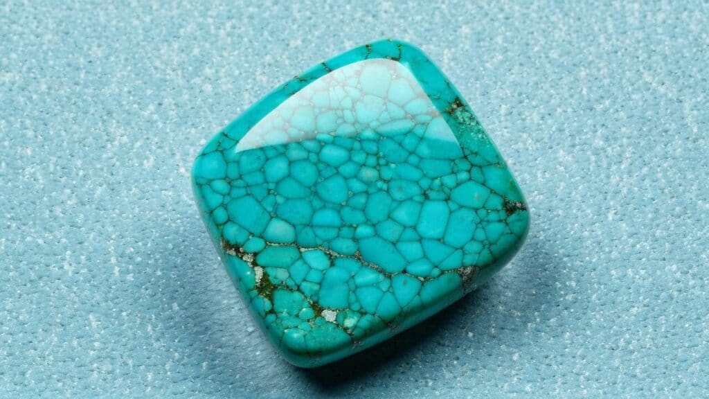 Polished turquoise gemstone with a natural webbed pattern, benefiting from waxing and oiling treatments to maintain color and prevent discoloration.