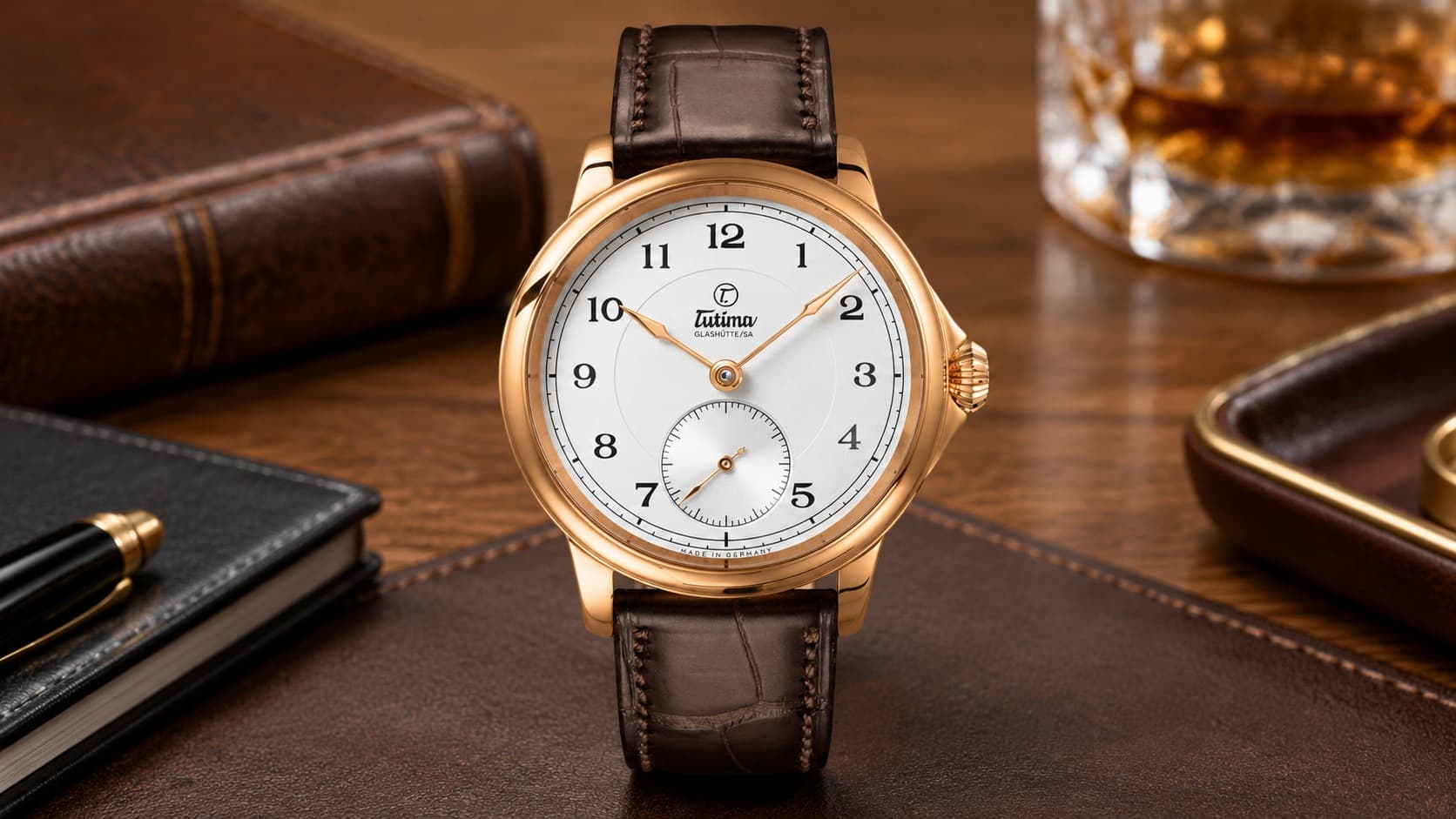 Tutima Glashütte Small Second 6600-01 rose gold watch with white dial and brown leather strap on a wooden desk