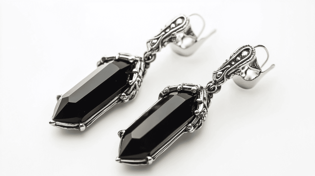 A pair of vintage-style dangle earrings featuring faceted black jet stones set in ornate silver metal.