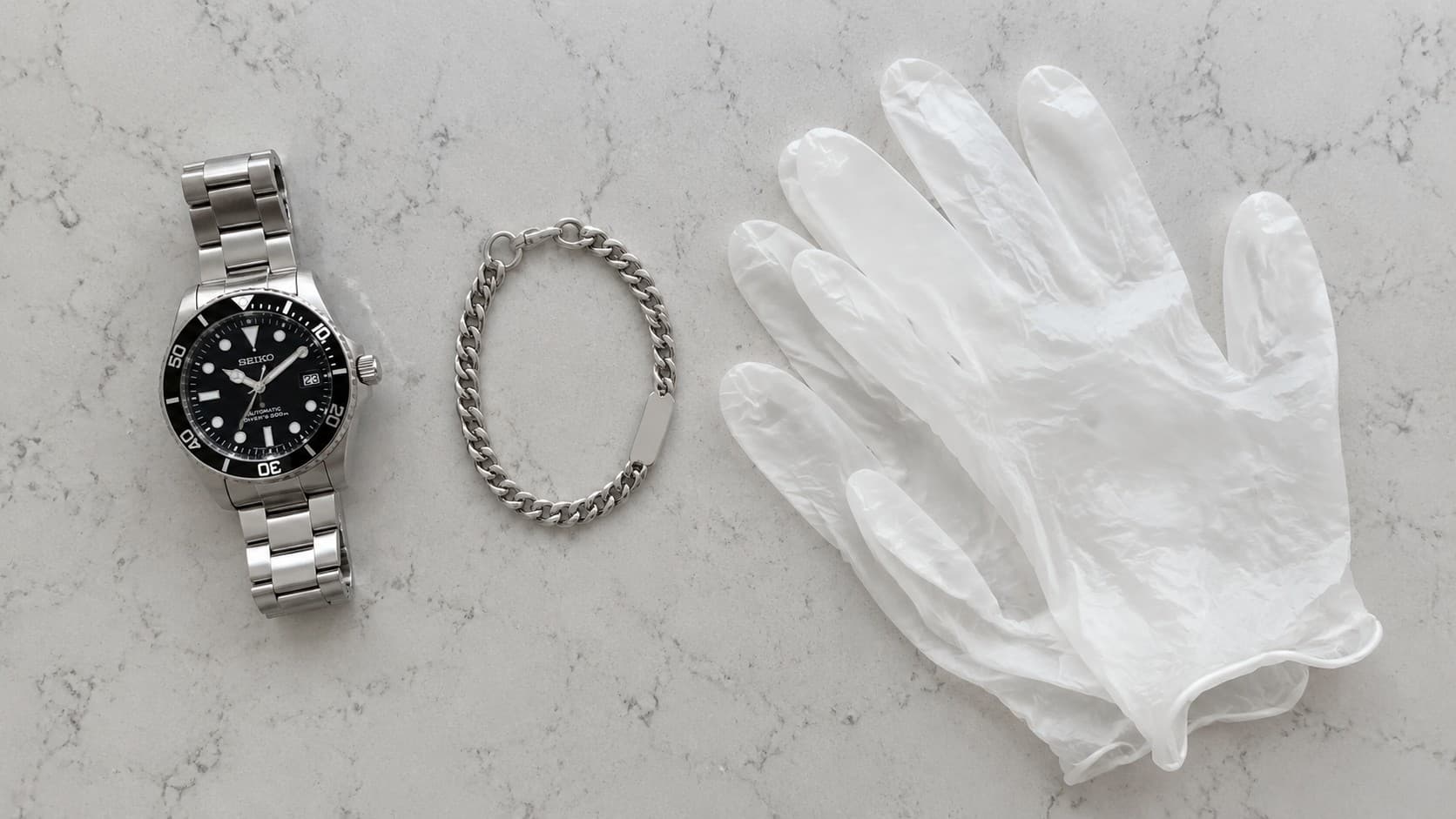 Watch, bracelet, and disposable gloves laid out to represent food handler jewelry rules