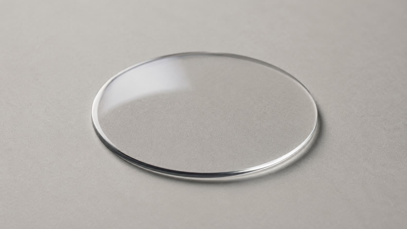 Clear round watch crystal lying on a flat surface