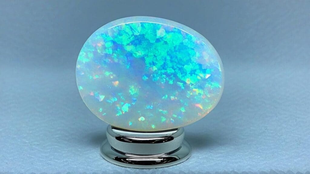 An oval white opal gemstone showing a mesmerizing play-of-color. Opals are treasured by gemstone collectors for their unique iridescence and rarity.