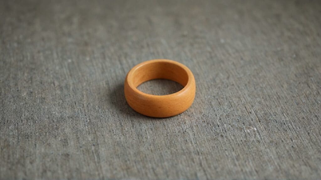 Wooden ring on textured surface showing safe alternative jewelry material for sauna use