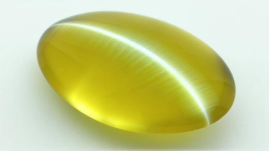 Yellow cat's eye chrysoberyl gemstone showing sharp chatoyancy under direct light