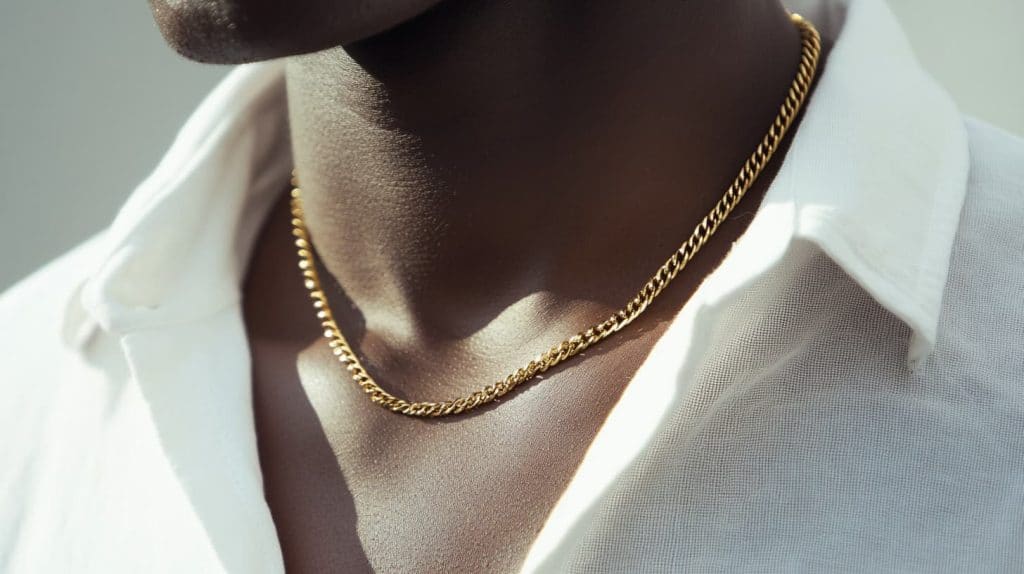 A yellow gold chain necklace worn over a white shirt, demonstrating its classic design and tarnish-resistant properties for everyday wear.