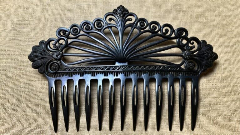 Antique Victorian gutta percha hair comb with intricate filigree and floral carvings, a popular mourning jewelry accessory from the 19th century.