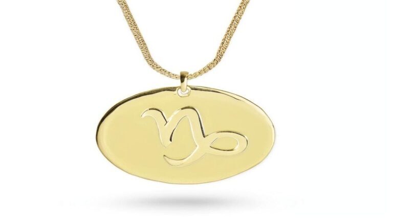 Gold oval medallion pendant featuring the Capricorn zodiac symbol cutout design, suspended on a textured gold chain.
