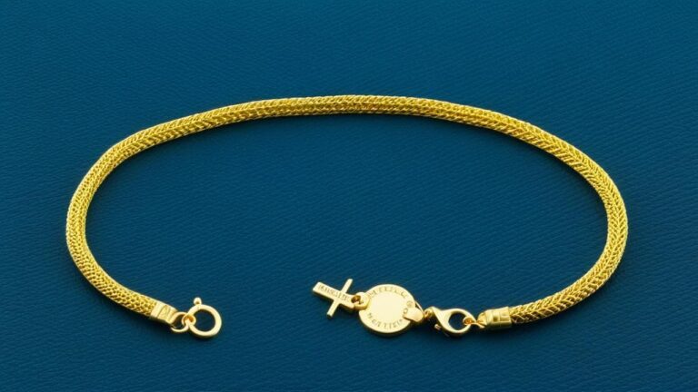 Delicate woven gold vermeil chain bracelet with a secure clasp, displayed on a blue background.