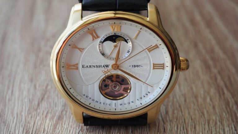 Earnshaw automatic watch with skeleton dial, moonphase complication, and gold-tone case displaying mechanical movement through open aperture