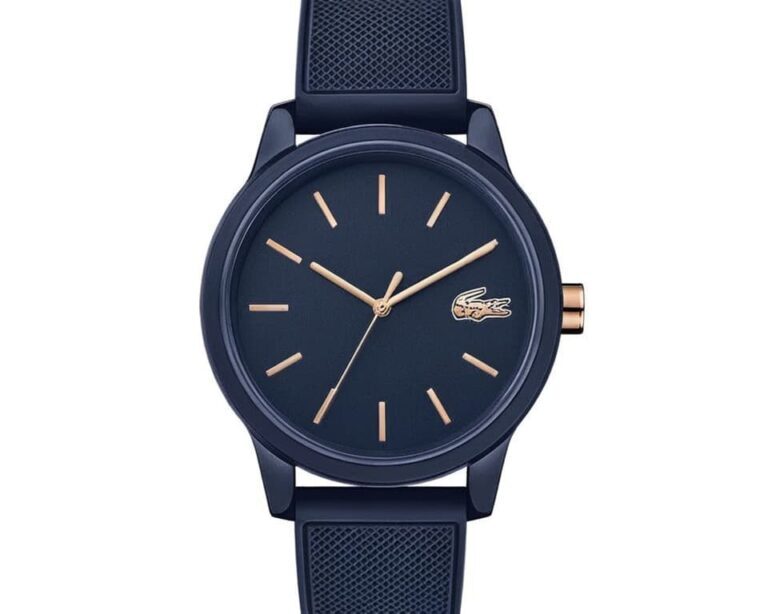Lacoste navy blue watch featuring rose gold hour markers and hands, matching textured silicone strap, and small crocodile logo at 3 o'clock